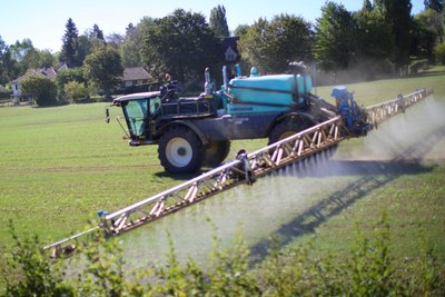 Agricultural machinery spraying fields, illustrating land use change and pollution
