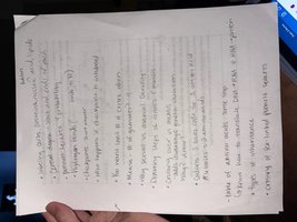 A hand holding a piece of paper with handwritten biology notes