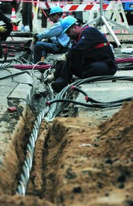 Workers repairing a cut underground cable, illustrating a discontinuity in voltage over time.