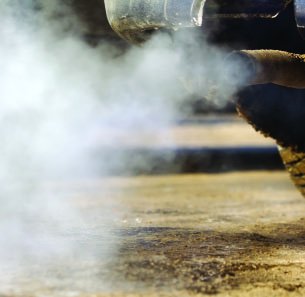 Car exhaust emitting gases, illustrating a chemical equilibrium involving carbon monoxide and oxygen