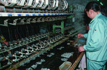 Harvesting silk fibers from cocoons in a factory