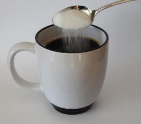 Photo of sugar being added to coffee as an example of a solution