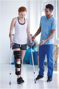 Physical therapist assisting a patient with a fractured leg