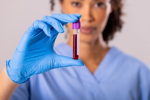Gloved healthcare worker holding a blood sample tube