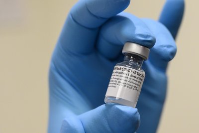 Gloved hand holding a vaccine vial