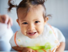 Toddler smiling and self-feeding