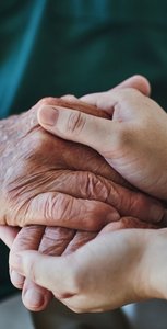 Hands of older adult being held, symbolizing support and care