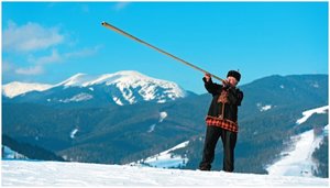 Person playing a long horn in the mountains, illustrating sound propagation in air
