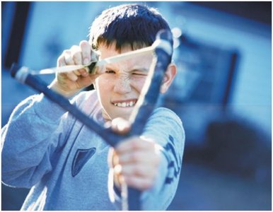 Boy pulling a slingshot, storing elastic potential energy.