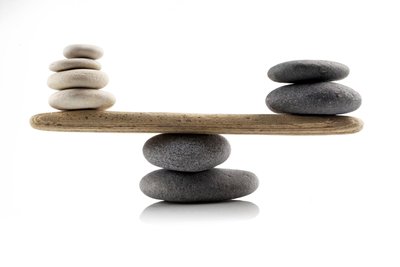 Balanced stones on a seesaw, illustrating equilibrium