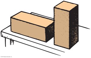 Two bricks, one lying flat and one standing upright, illustrating pressure difference due to area