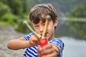 Boy pulling back a slingshot, demonstrating work done to increase elastic potential energy