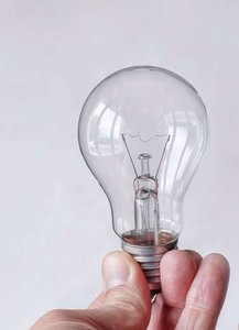 A hand holding a light bulb, representing a resistive load