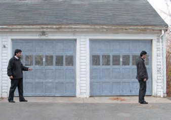Two people standing at different positions in front of a garage, illustrating initial and final positions for displacement