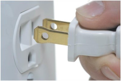 Plug being inserted into a wall socket, illustrating household AC voltage