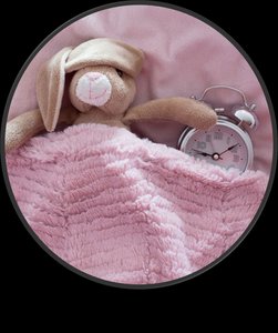 Stuffed animal in bed with alarm clock, representing sleep routines