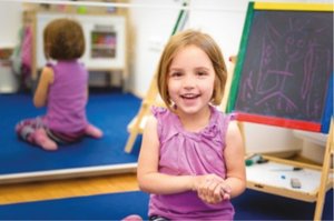 Child in front of a chalkboard, demonstrating creative fine motor activity