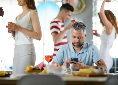 A person feeling isolated at a social event, representing chronic adversity or social stress