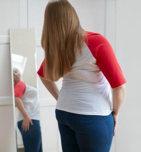 Woman looking at herself in a mirror, relevant to mirror presence in exercise settings