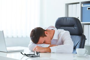 Person falling asleep at desk, illustrating the biological urge to sleep