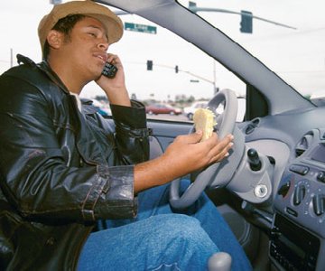 Person driving while talking on the phone and eating, demonstrating multitasking