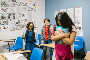 Children in a classroom, one appearing isolated, illustrating bullying